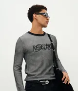 Suéter de punto para hombre, color gris con rayas verticales negras, cuello redondo y mangas largas. Cuenta con un estampado frontal con la inscripción "Rebellion" en tipografía gótica.