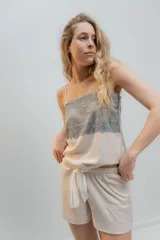 Pijama de dos piezas, compuesto por una musculosa blanca con detalle de puntilla negra elástica en el escote y un short blanco con elástico y lazo negro en la cintura.