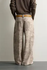 Pantalón relaxed fit de algodón con estampado animal print de cocodrilo en tonos beige y gris. Tiene diseño de cinco bolsillos, cierre frontal con cremallera y botón, y una tira con bolsillo multifunción en la pernera.