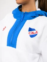 Buzo de micropolar color bordó con capucha, cierre frontal parcial y detalles en color crema. Presenta el logo de Umbro y el escudo del Club Nacional de Football bordados en el frente.