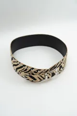 Cinturón de cuero con estampado animal print de cebra, decorado con tachas metálicas plateadas a lo largo de los bordes y hebilla metálica plateada.