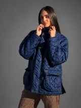 Campera marrón oscuro capitoneada, con diseño acolchado de rombos, cuello alto, cierre frontal con botones metálicos y grandes bolsillos aplicados con solapa en el frente.