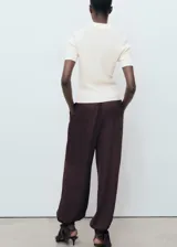 Jersey de punto fino color blanco crudo, con cuello polo, manga corta y diseño entallado con canalé.