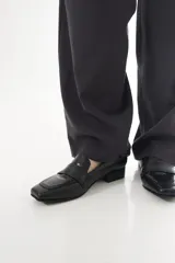 Mocasines negros de cuero vacuno con punta cuadrada, taco bajo y detalle texturizado tipo lagarto en el empeine.