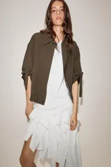 Chaqueta bomber color marrón, con cuello solapa, cierre frontal oculto con cremallera y botones a presión. Presenta mangas remangadas con trabillas y bajo abullonado con elástico interior.