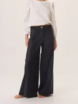 Pantalon de pierna ancha color azul marino, con costuras decorativas en contraste de color rojo y franjas laterales a tono. Cuenta con cintura alta, cierre frontal y bolsillos laterales.