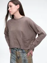 Sweater de tejido de punto color beige, con cuello redondo, hombros caídos y costura central vertical en el frente. Presenta un diseño de corte relajado, con largo asimétrico y aberturas laterales en el ruedo.