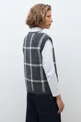 Chaleco de punto jacquard con diseño de cuadros, cuello redondo y cierre frontal con botones.