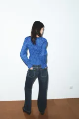 Camisa de manga larga con cuello redondo, confeccionada en tejido de cuadros vichy en tonos de azul. Presenta un fruncido elástico en el torso y puños con elástico.