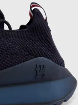 Zapatillas de running Tommy Hilfiger color azul marino, confeccionadas en tejido de punto elástico de poliéster reciclado. Cuentan con plantilla de acupresión, suela dentada de goma y caucho, trabilla distintiva y monograma TH grabado en la entresuela.
