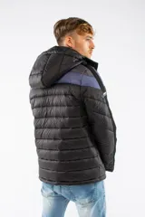 Campera puffer de nylon con relleno de guata, diseño capitoneado y capucha desmontable. Presenta un patrón de chevron en color azul sobre base negra, cierre frontal y bolsillos laterales con cierre.