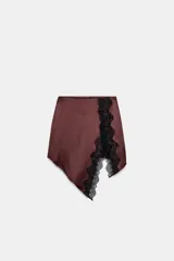 Falda mini de tejido satinado color bordó, con detalle de encaje negro en el frente y bajo asimétrico con abertura.