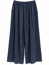Pantalón ancho color azul marino con cintura elástica fruncida, bolsillos laterales y detalle de botones en los tobillos.