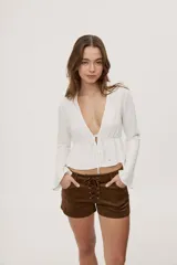 Short de tiro bajo con textura efecto gamuza color beige, bolsillos delanteros y detalle de cordones entrecruzados en la parte frontal.