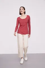 Remera blanca de manga larga, entallada, con cuello redondo y una hilera de botones en el frente. Incluye un pequeño bolsillo decorativo en el pecho.