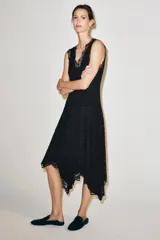 Vestido midi negro confeccionado en encaje de algodón, con escote en pico, diseño sin mangas, forro interior y bajo asimétrico.