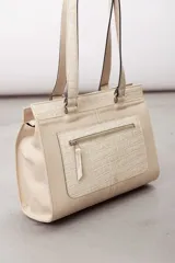 Cartera de cuero marrón de tamaño medio con diseño estructurado, que combina cuero liso y un panel frontal texturizado tipo cocodrilo con bolsillo exterior con cierre. Cuenta con doble asa de hombro y costuras visibles de contraste.