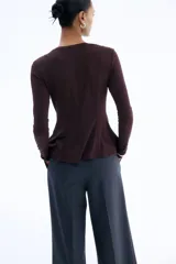 Top de manga larga en punto de crepé, con cuello redondo y diseño con peplum. Presenta costuras moldeadoras en la parte frontal y posterior que definen la silueta.