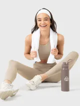 Conjunto deportivo de dos piezas compuesto por un top deportivo de escote redondo y calzas largas de tiro alto, ambos en color beige. El set destaca por su diseño minimalista y ajuste cómodo.
