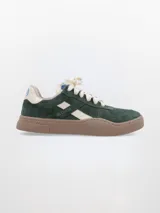 Zapatillas de cuero verde oscuro con detalles en blanco hueso, suela marrón y cordones blancos.