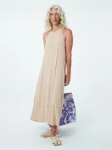 Vestido largo color beige, con cuello halter y corte recto.