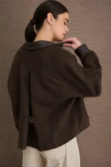 Campera de paño marrón con detalles en cuero sintético en cuello, puños y solapas de bolsillos. Presenta cierre frontal con botones dorados y dos bolsillos delanteros tipo cargo.
