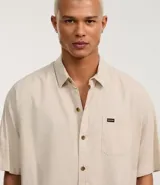 Camisa de corte relajado para hombre, confeccionada en una mezcla de cáñamo y algodón. Presenta cuello inglés, manga corta, cierre frontal con botones y un bolsillo en el pecho con una pequeña etiqueta aplicada.