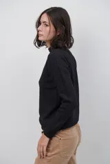 Polera de tejido de punto fino en color beige, con cuello alto y mangas largas con puños acanalados.
