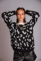 Buzo de punto color negro con estampado animal print en gris claro, de corte holgado y manga larga.