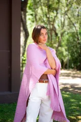 Ruana tejida color rosa con flecos en el borde inferior.