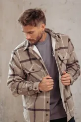 Sobrecamisa de corte holgado con diseño a cuadros en tonos azul marino y marrón, confeccionada con forro interior de corderito sintético, cuello clásico, cierre frontal de botones y bolsillos en el pecho.