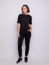 Pantalón tipo babucha de estilo deportivo, color negro, con cintura elástica ajustable mediante cordón, puños en los tobillos y bolsillos laterales.