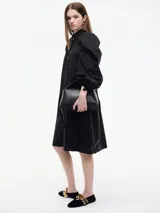 Vestido camisero blanco con botones frontales, cuello camisero, manga larga abullonada con puños ajustables y corte a la rodilla.