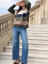 Sweater de tejido de punto artesanal en color verde oliva, con diseño de guardas geométricas y motivos botánicos bordados en tonos blanco, azul y rojo. Presenta cuello redondo, mangas largas y terminaciones en tejido acanalado.