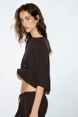 Top blanco de tejido rústico, con cuello redondo y mangas cortas amplias. Bajo recto.