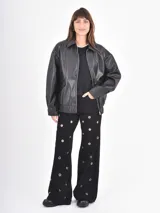 Jean de corte recto y tiro alto, color negro, con diseño de ojales metálicos distribuidos por toda la prenda.