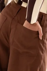 Pantalon de tiro medio con silueta curvada, mas ancha en la zona del muslo y la rodilla, con bolsillos laterales y cierre frontal con cremallera y boton.