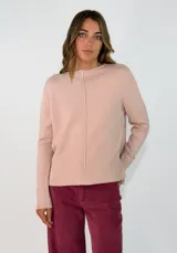 Sweater de punto color rosado, con cuello redondo, manga larga y detalle de costura vertical central. Presenta puños y ruedo acanalados, con un diseño de largo asimétrico, siendo más corto en la parte delantera y más largo en la parte trasera.