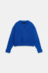 Jersey de punto color azul eléctrico con escote en pico, manga larga y detalle de costuras marcadas en los hombros. Presenta un corte ligeramente cropped con puños y ruedo acanalados.
