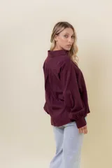 Camisa de manga larga color bordó oscuro, con cuello clásico y bordado calado decorativo en el área del pecho y hombros. Presenta un calce relajado y cierre frontal de botones.