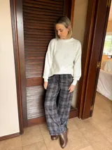 Sweater de punto acanalado en color natural, con cuello redondo, mangas largas con puños ajustados y diseño holgado con aberturas laterales en el ruedo.
