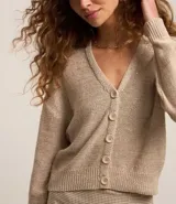 Cardigan color beige confeccionado en tejido de punto con lentejuelas, de corte regular, cuello en V, manga larga y cierre abotonado frontal.