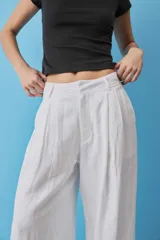Pantalon blanco de lino de pierna ancha y tiro alto, con pinzas frontales y bolsillos laterales.