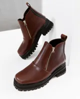 Bota de cuero vacuno color marrón, con interior forrado en corderito natural. Tiene suela de goma artesanal, punta cuadrada, cierre YKK en ambos lados y caña de 11cm.
