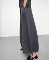 Pantalón gris oscuro de tejido plisado (crinkle), con cintura elástica, bolsillos laterales y diseño de pierna ancha.