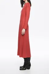 Vestido midi de cupro color negro, con corte línea A y vuelo. Cuenta con escote barco, manga larga y costuras con pespuntes decorativos a contraste.
