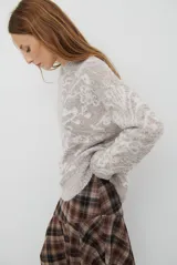 Buzo de tejido de punto en color marrón con un patrón ornamental floral en color celeste. Presenta cuello redondo, mangas largas y un corte holgado.