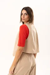Chaleco de corte sastre en color beige, con escote en V, cierre frontal mediante botones y costuras decorativas en contraste.