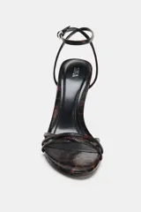 Sandalia de tacón alto fino con diseño de tiras finas en la parte delantera. Presenta un estampado animal print en tonos marrones y negros, con cierre de pulsera al tobillo mediante hebilla ajustable.