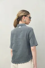 Camisa blanca de manga corta confeccionada en algodón, con bordados a tono y terminaciones festoneadas. Presenta cuello clásico y silueta recta.